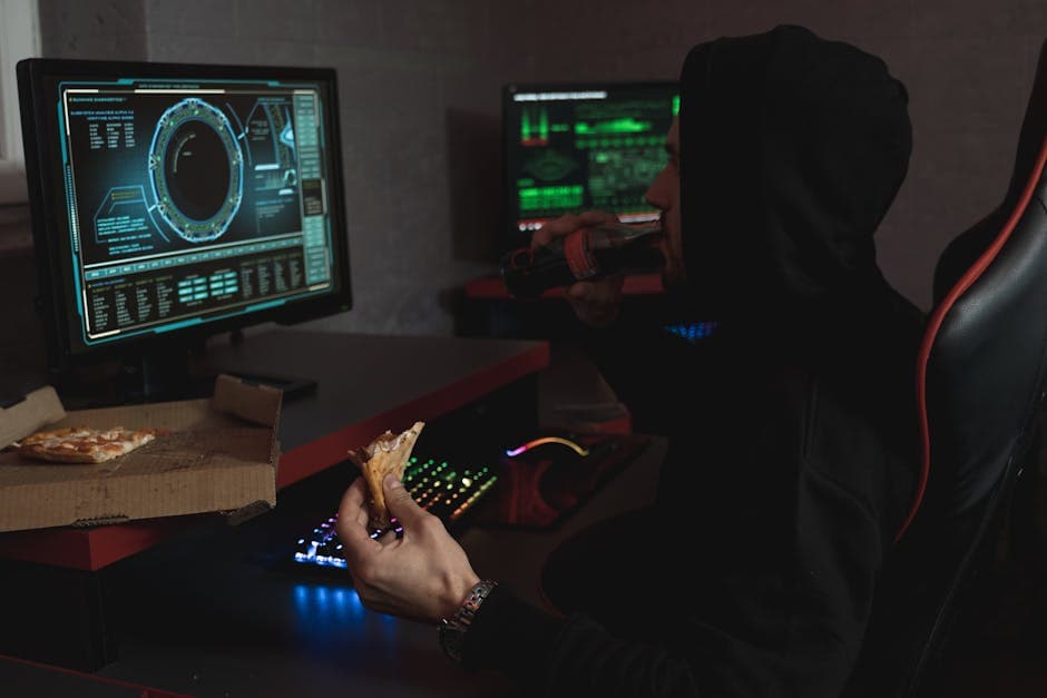 Hacker in a black hoodie eating pizza and drinking soda while analyzing data on multiple computer screens.