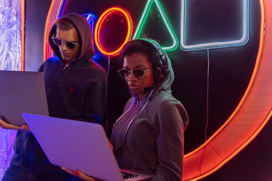 Two cybersecurity experts working on laptops at night with neon lights in the background.
