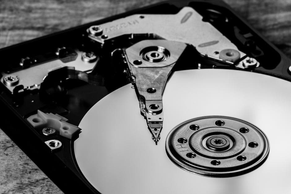 Detailed black and white image of an open hard drive, showcasing intricate components.