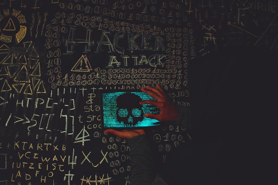 A hacker in a black hoodie using a tablet displaying a skull, surrounded by chalk symbols and 'Hacker Attack' text.