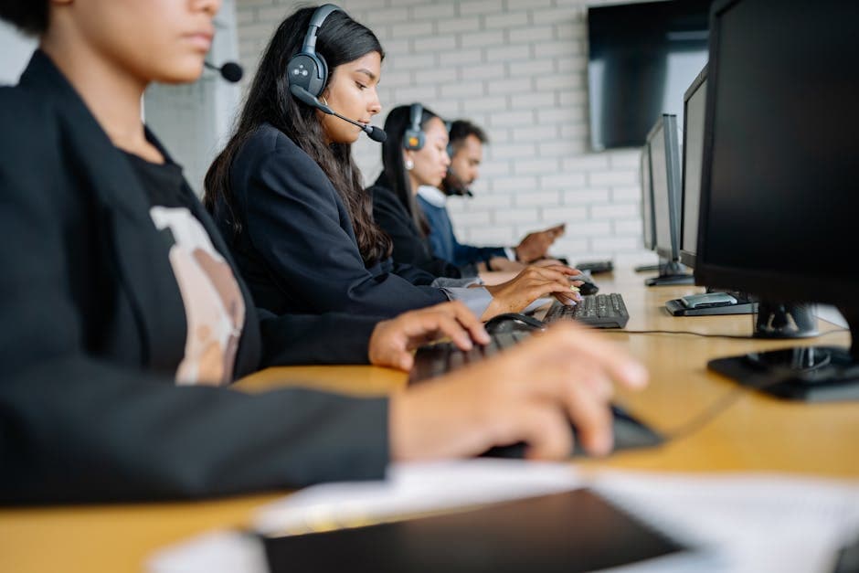 Team of professionals working in a call center with headsets and computers.