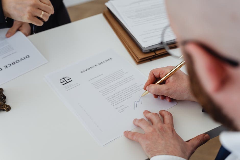 Close-up of a person signing a divorce decree on a desk.