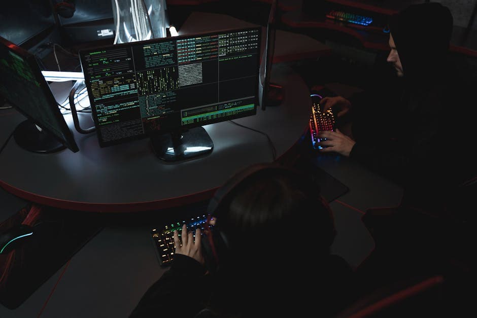 A group of people in a dark room working on computers, related to cybersecurity.