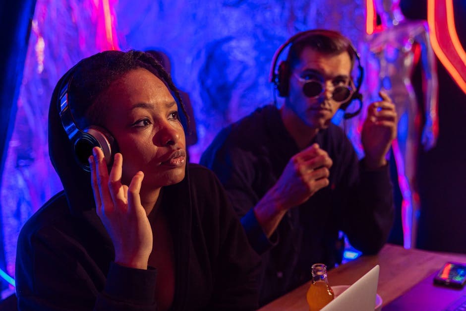 Two adults with headphones in a lively, colorful nightclub setting, focused and engaged.